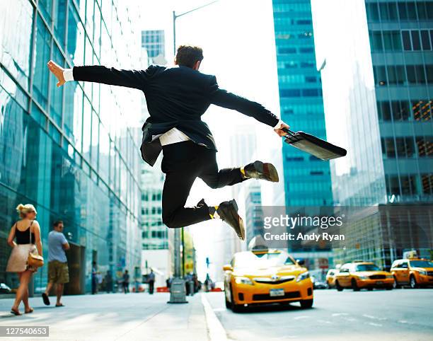 businessman jumping for joy on city street. - car mid air stock pictures, royalty-free photos & images