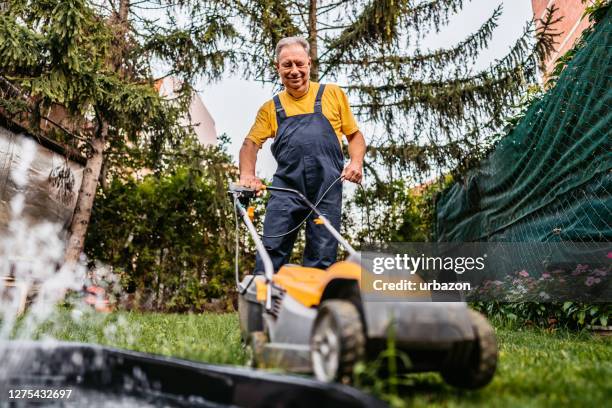 mann mäht den rasen - rasenmäher stock-fotos und bilder