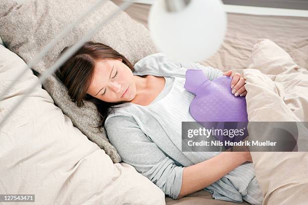 woman sleeping with hot water bottle - wärmflasche stock-fotos und bilder