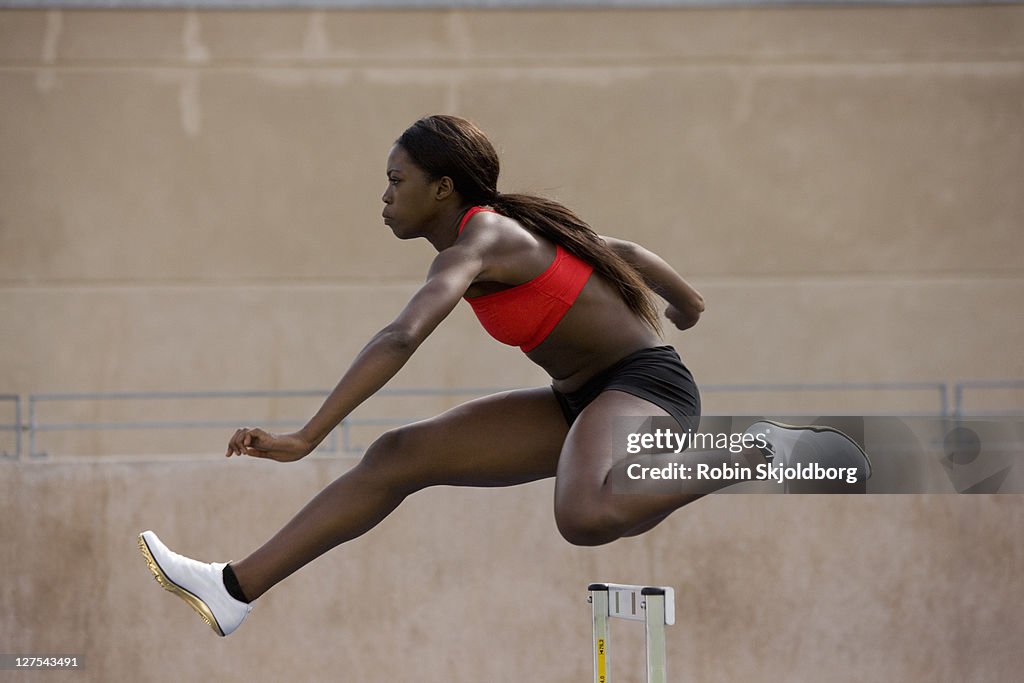 Runner jumping over hurdles on track