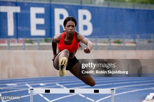 Runner jumping over hurdles on track Runner jumping over hurdles on track