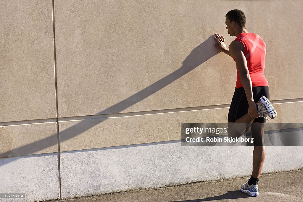 Man stretching against wall