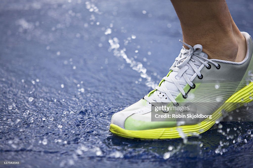 Running shoe splashing water on track