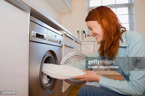 woman unloading washing machine - washing machine photos et images de collection