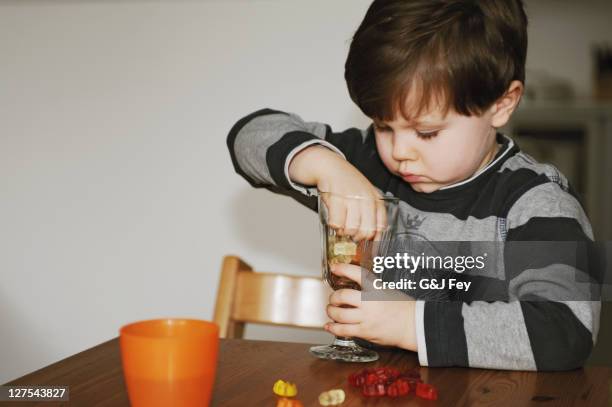 boy playing with candy at table - kid reaching for stock pictures, royalty-free photos & images