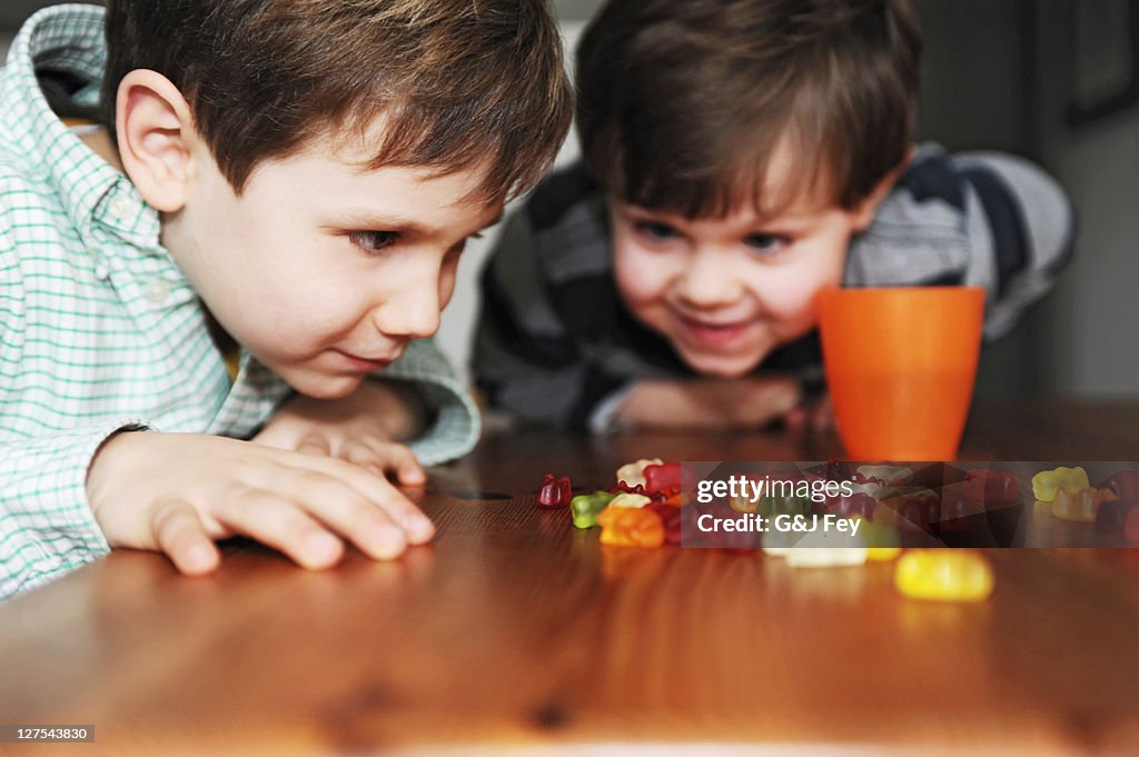 Jungen spielen mit Süßigkeiten auf Tisch