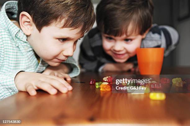 boys playing with candy at table - gummi bears stockfoto's en -beelden