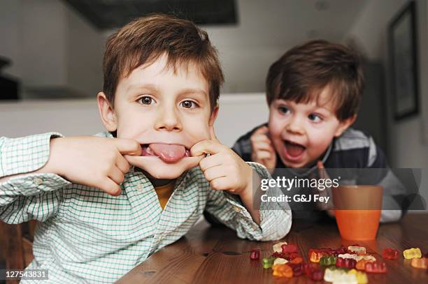 boys making faces at table - candy on tongue stock pictures, royalty-free photos & images