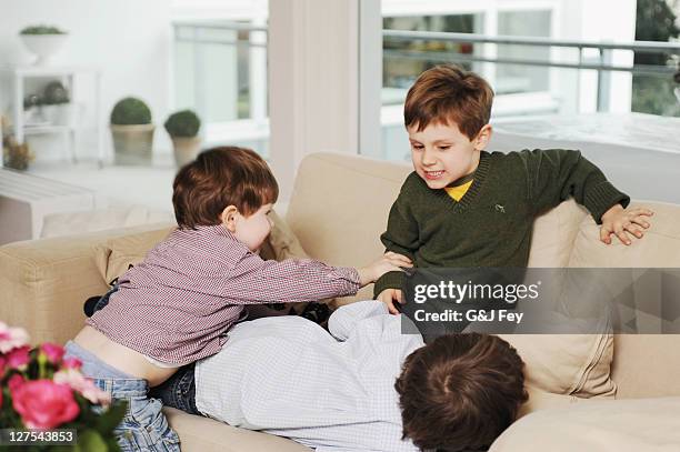 boys playing on the sofa - stoeien stockfoto's en -beelden