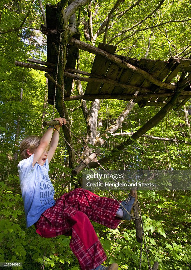 Boy climbing rope ladder in tree house