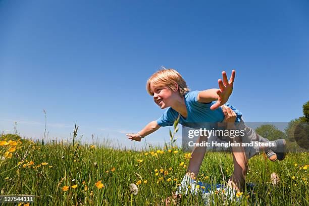 father and son playing airplane in field - bayern menschen stock-fotos und bilder