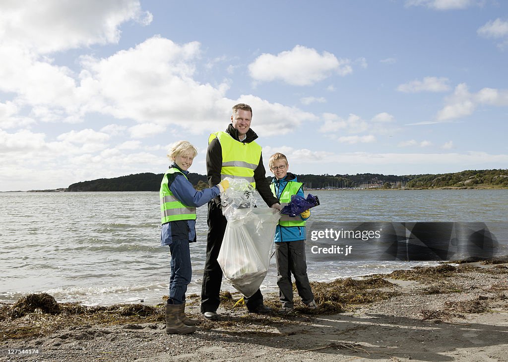 Father and sons cleaning beach