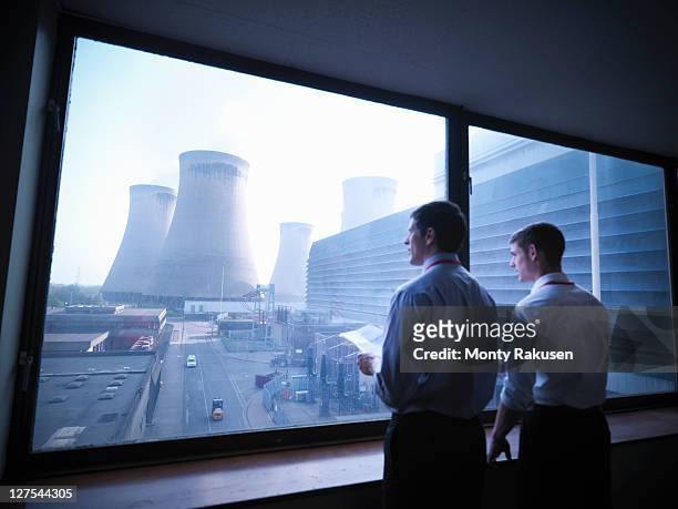 workers looking out over power station - nuclear energy photos et images de collection