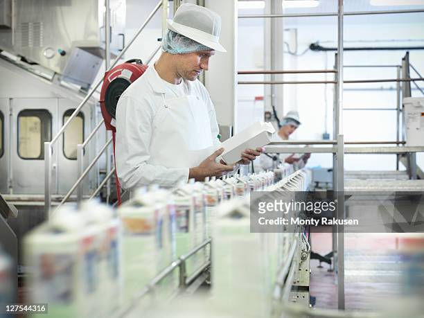 worker inspecting goat's milk in dairy - routine foto e immagini stock