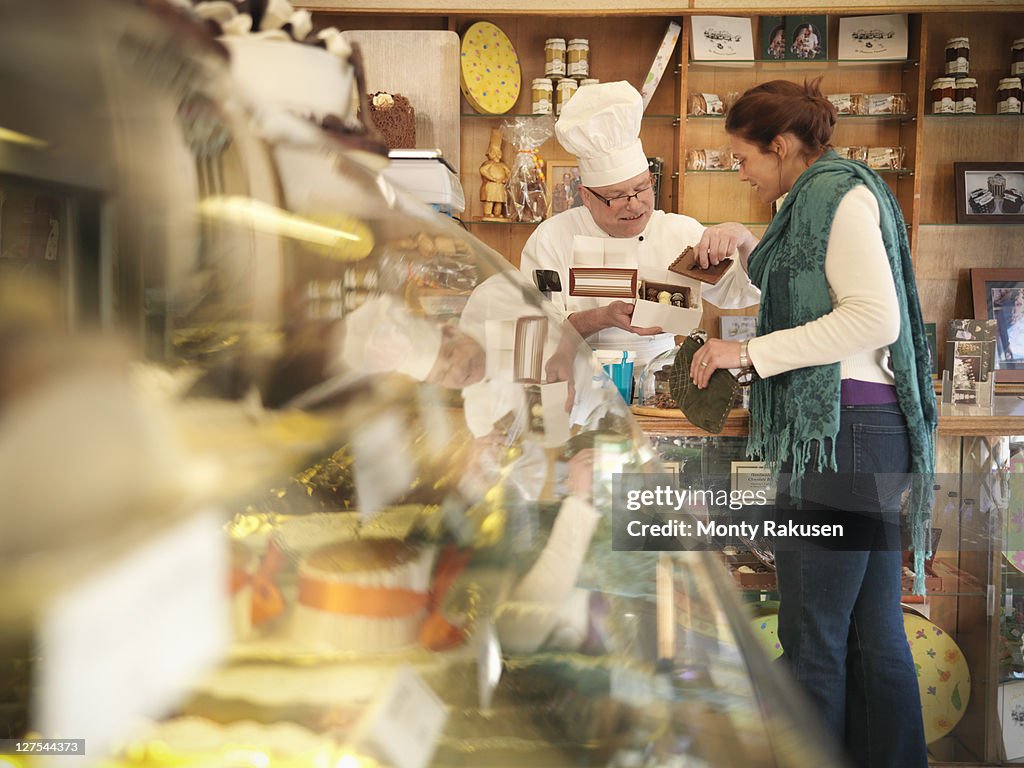 Baker with customer in cake shop