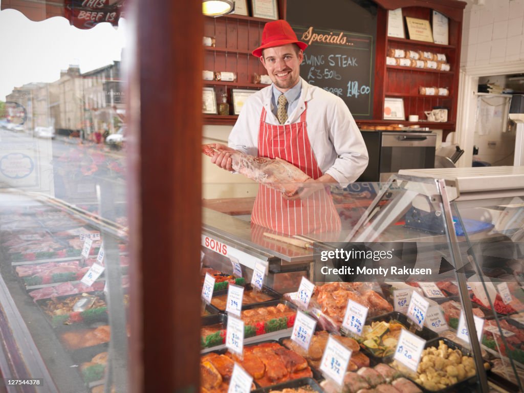 Butcher holding leg of lamb in shop