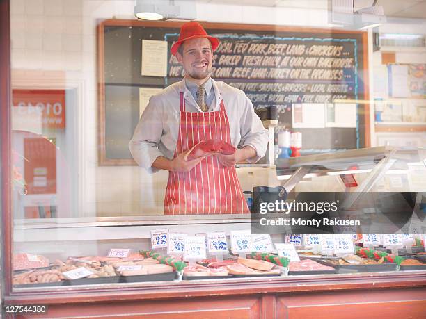 butcher holding steak behind counter - butcher stock pictures, royalty-free photos & images