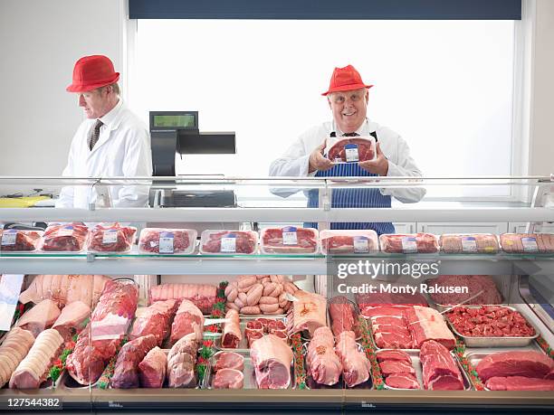 butcher standing behind meat counter - präsentation hinter glas stock-fotos und bilder