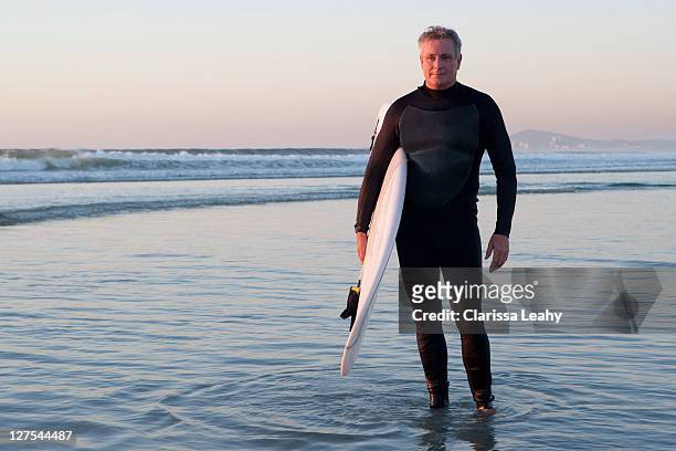 surfer stehend im wasser - beach hold surfboard stock-fotos und bilder