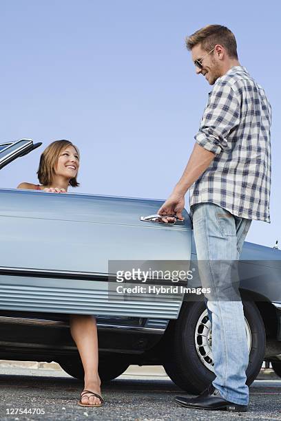 man opening car door for girlfriend - open car door stock pictures, royalty-free photos & images