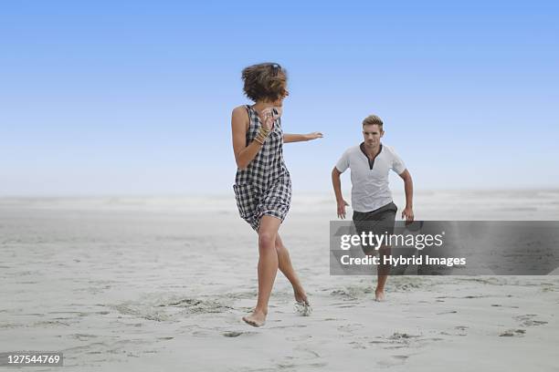 couple chasing each other on beach - hermanus stock pictures, royalty-free photos & images