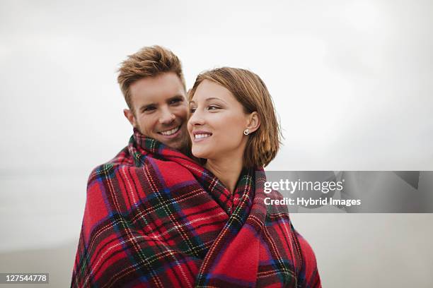 couple wrapped in blanket on beach - hermanus stock pictures, royalty-free photos & images