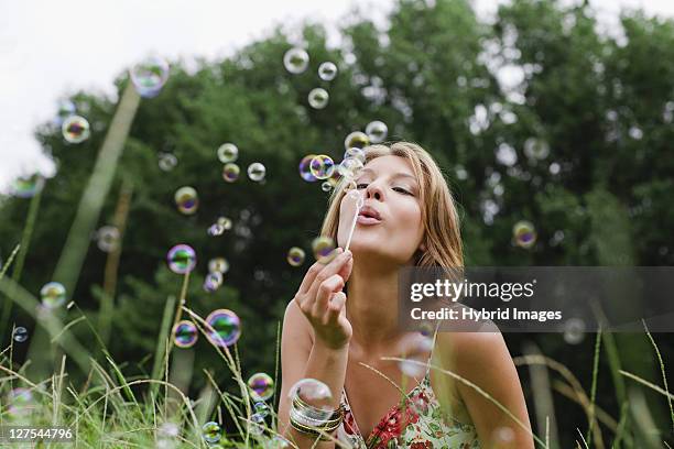 woman blowing bubbles in field - hermanus stock pictures, royalty-free photos & images