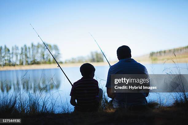 father fishing with son in lake - kids fishing stock pictures, royalty-free photos & images