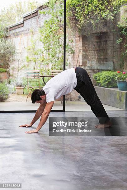 man practicing downward dog yoga pose - downward facing dog position stock pictures, royalty-free photos & images