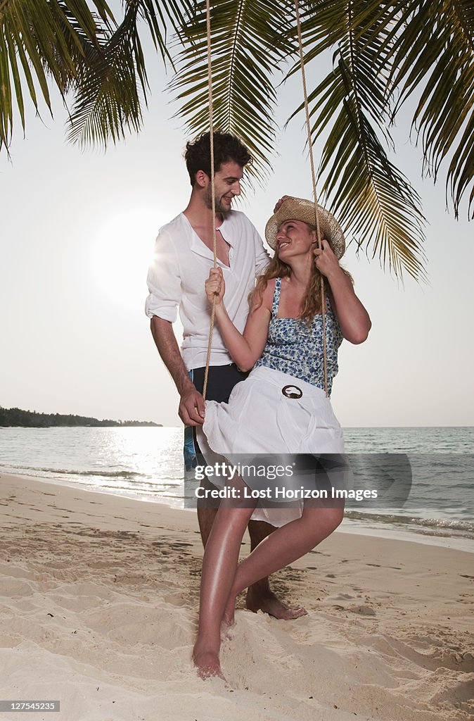 Couple playing on swing at beach