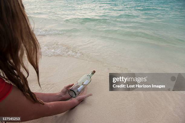 woman with message in a bottle at beach - message in a bottle stock pictures, royalty-free photos & images