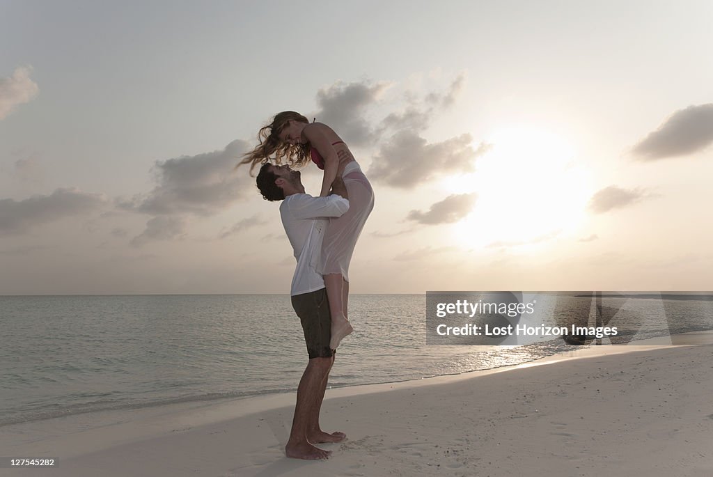 Couple playing on beach at sunset