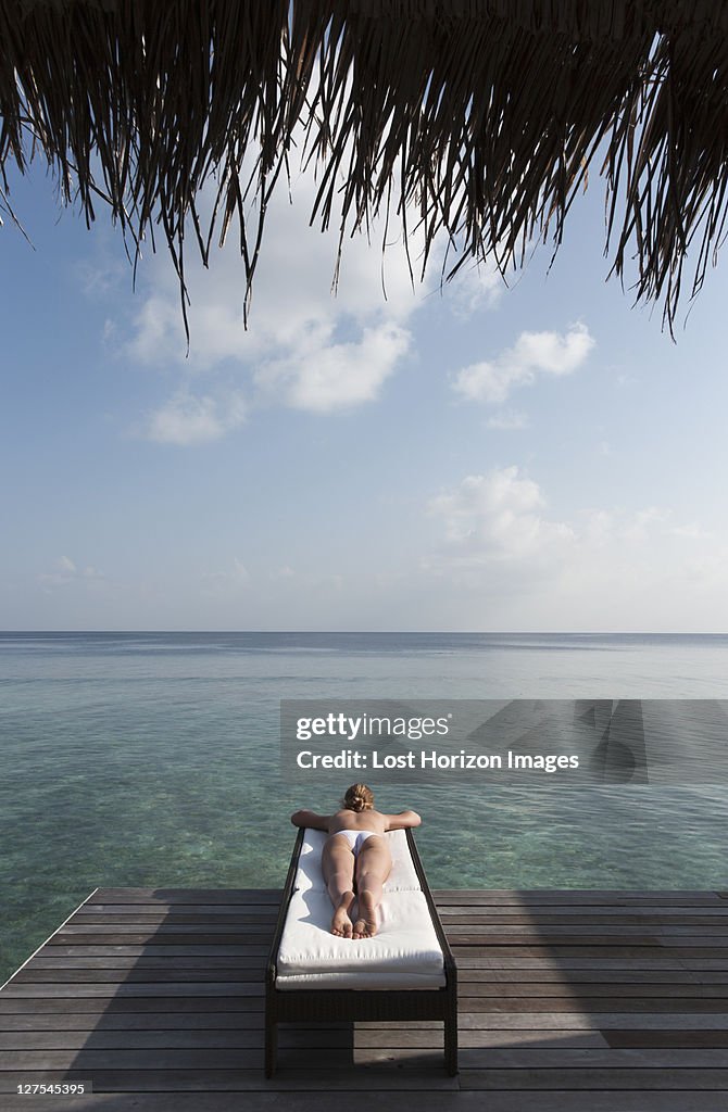 Woman laying on deck overlooking sea