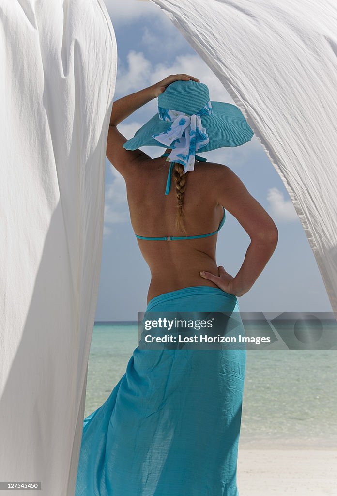 Mujer detrás de las cortinas de color blanco en la playa