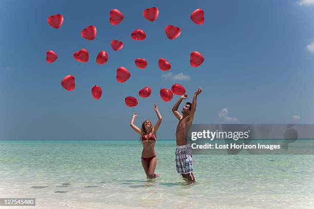 couple playing with balloons on beach - falling in love stock pictures, royalty-free photos & images