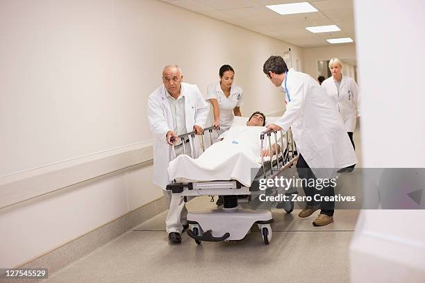doctors rushing patient down hallway - hospital gurney stock pictures, royalty-free photos & images