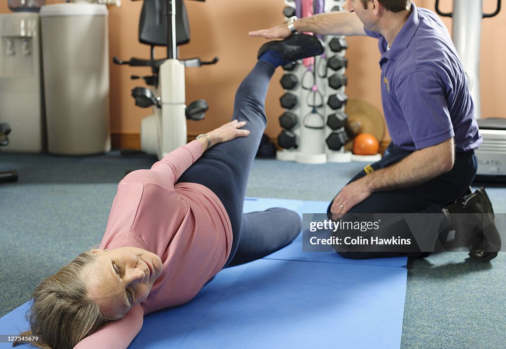 Trainer helping older woman exercise