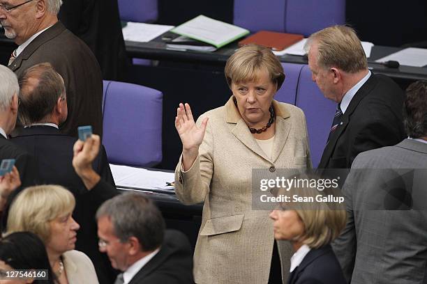 German Chancellor Angela Merkel chats with a colleague shortly after casting her ballot along with other Bundestag members in voting on an increase...