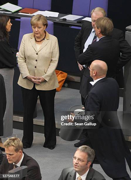 German Chancellor Angela Merkel chats with a colleague as a Bundestag aide carries a ballot box away shortly after Bundestag members voted on an...