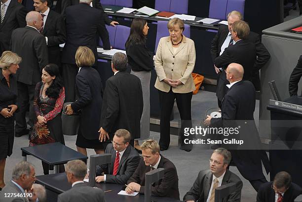 German Chancellor Angela Merkel chats with a colleague as a Bundestag aide carries a ballot box away shortly after Bundestag members voted on an...