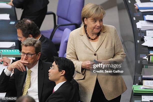 German Chancellor Angela Merkel holds her ballot before voting on an increase in funding for the European Financial Stability Facility as she walks...