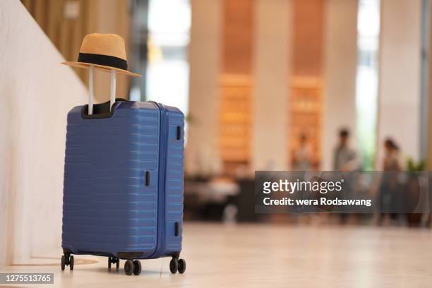 luggage with sun hat placing in front of hotel lobby isolated over hotel reception blurred background - suitcase stock pictures, royalty-free photos & images