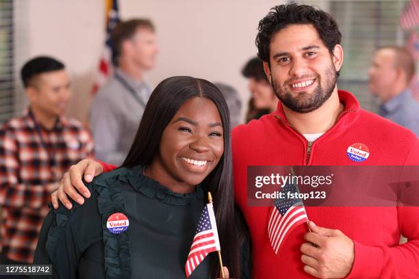 mixed race couple is all smiles as they vote in usa election. - voting booth stock pictures, royalty-free photos & images