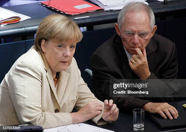 Angela Merkel, Germany's chancellor, left, pauses as she speaks with Wolfgang Schaeuble, Germany's finance minister, ahead of a vote to expanded the...