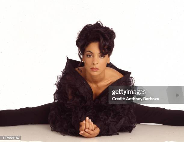 Portrait of American actress Jasmine Guy, dressed in black, as she poses on the floor against a white background, 2000.