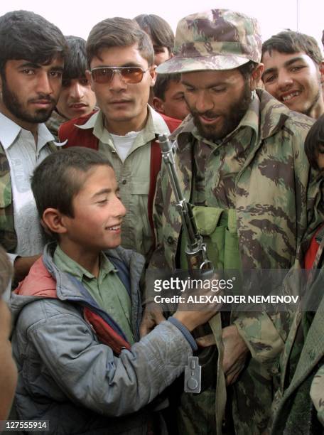 Northern Alliance soldier shows his Kalashnikov to a local boy in Kabul, 13 November 2001, after Northern Alliance captured the Aghani capital....