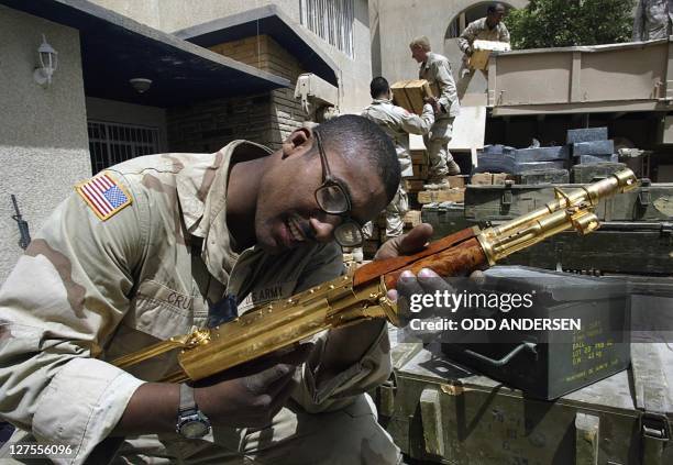 Soldier from the 3rd Infantry Division takes a close look at a golden Kalashnikov ingraved with an Arabic sentence reading "A gift from Iraqi...