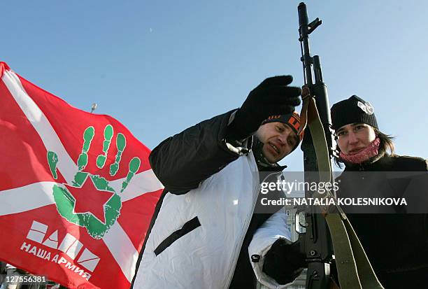 Young man and a girl hold a Kalashnikov submachine gun during a rally devoted to the national holiday celebrations, the Day of the Fatherland's...