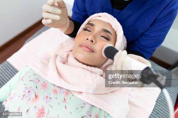 de schoonheidsspecialist maakt de procedure microdermabrasion van de gezichtshuid van een mooie, jonge vrouw in een schoonheidssalon - hyperpigmentation stockfoto's en -beelden