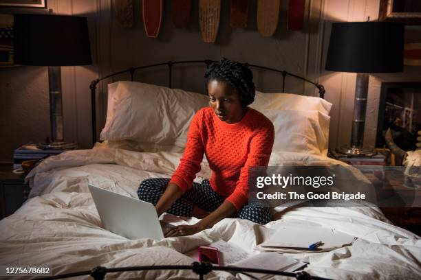 young woman working on laptop in bedroom - working overtime stock pictures, royalty-free photos & images